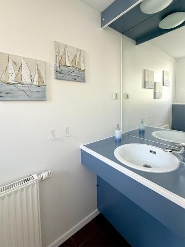 a bathroom with a sink and a mirror with boats on the wall at Steuerbord in Prerow