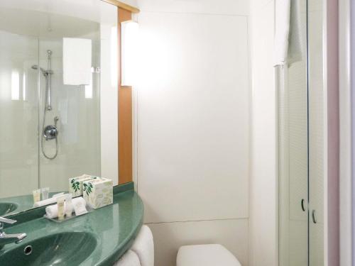 a bathroom with a green sink and a toilet at ibis Thornleigh in Thornleigh