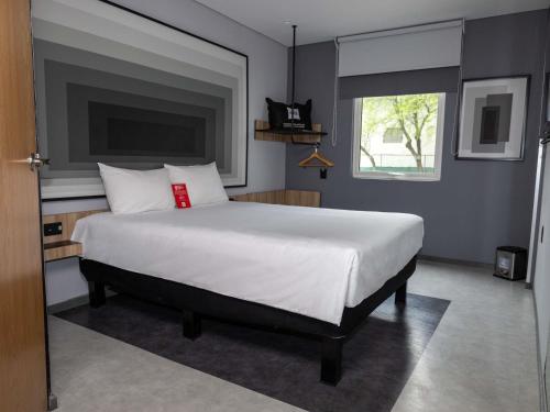 a bedroom with a large white bed with a window at Ibis Monterrey Aeropuerto in Monterrey