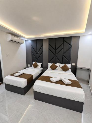 two beds in a hotel room with towels on them at Hotel Lime Wood Mangaluru in Mangalore