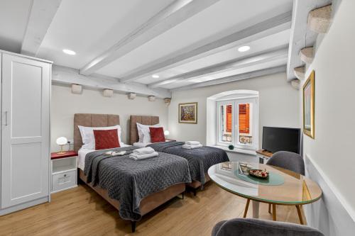 a bedroom with two beds and a table at Solis Rooms Old Town in Dubrovnik