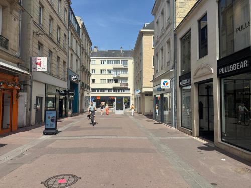 a person riding a bike down a street with buildings at Lovely Amour Hyper Centre in Caen