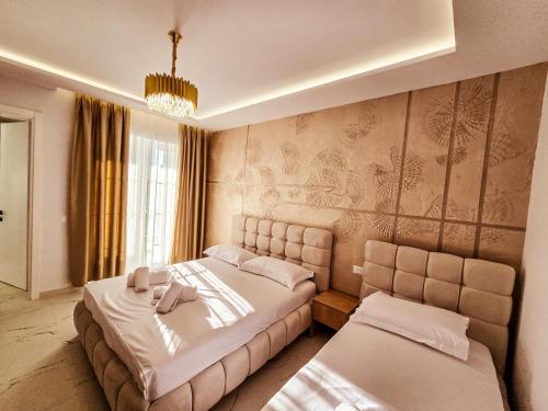 ein Schlafzimmer mit zwei Betten und einem Kronleuchter in der Unterkunft Hotel Kosova in Velipojë