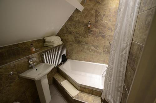 een badkamer met een bad, een wastafel en een douche bij The Harboro Hotel in Melton Mowbray