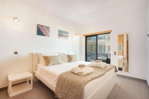 a bedroom with a large white bed with a window at Parque Atlântico Apartment in Quarteira