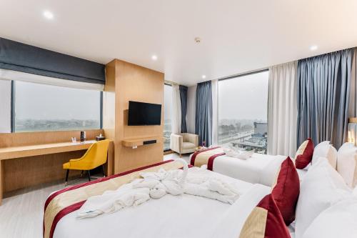 a hotel room with two beds and a desk at Lords CBC Plaza Chitwan in Bharatpur