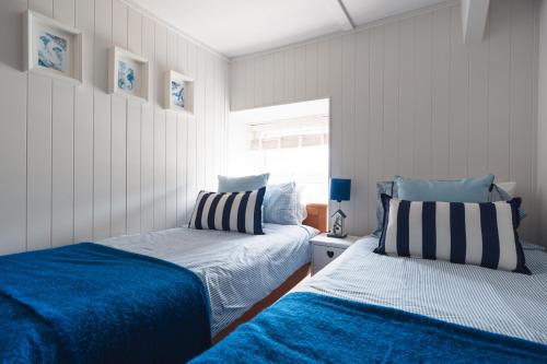 two beds in a bedroom with blue and white at Gerallt in Pwllheli