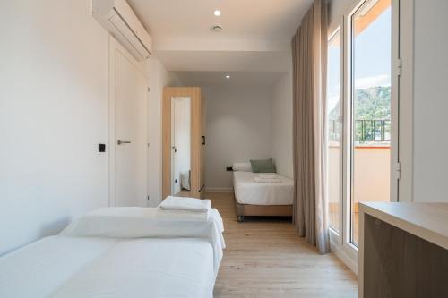 a white room with two beds and a window at Hotel Coral Boutique by gaiarooms in L'Estartit