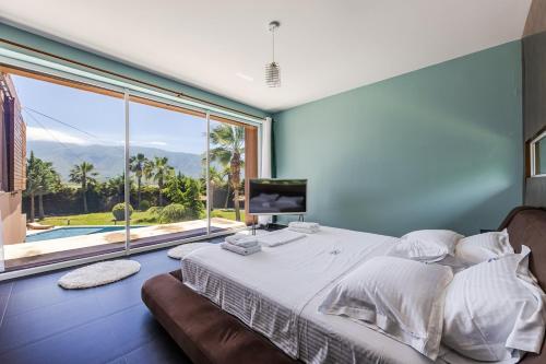 a bedroom with a large bed and a large window at Fllad e Valë Luxury Private Pool Villa by PikHost in Tragjas