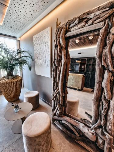 Ein aus Treibholz gefertigter Spiegel in einer Lobby mit Hockern in der Unterkunft John's Lodge in Les Collons