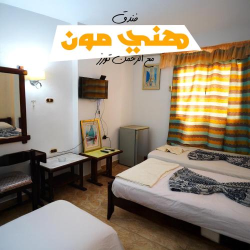a room with three beds and a sign on the wall at Honeymoon Hotel Marsa matrouh in Marsa Matruh