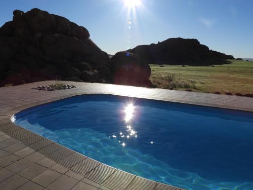 a blue swimming pool with a mountain in the background at Namib Naukluft Lodge in Solitaire