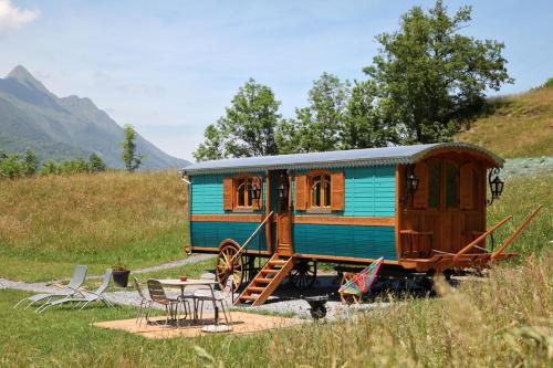 ein blauer Waggon, der auf einem Feld mit einem Tisch parkt in der Unterkunft Roulottes Montagne Pyrenees in Luz-Saint-Sauveur