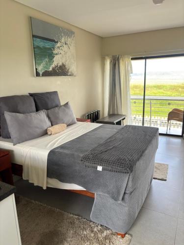 a bedroom with a large bed with a view of the ocean at Hlalanathi Lodges - Wagendrift Farm in Estcourt