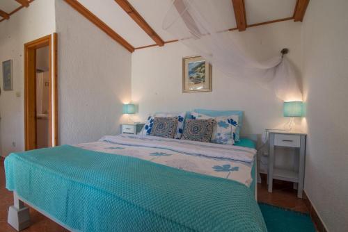 una camera da letto con un letto con lenzuola blu e due lampade di Roberto Apartments a Veli Lošinj (Lussingrande)