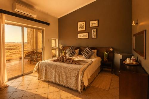 a bedroom with a bed and a sliding glass door at Namib Naukluft Lodge in Solitaire