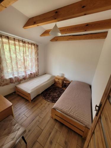 a bedroom with two beds in a room with wooden floors at Domki Strumieniowa in Wólka Tanewska