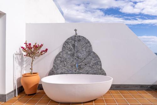 a bath tub in a bathroom with a rock wall at Apartamentos Islamar Arrecife in Arrecife