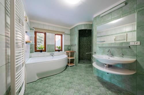 a bathroom with a tub and a sink and a bath tub at Chalet Drevarska in Benecko