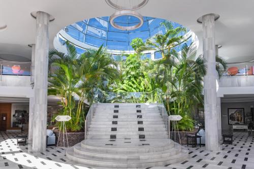 a lobby with a large building with palm trees at Elba Premium Suites - Adults Only in Playa Blanca