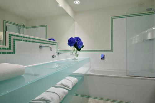 a bathroom with a tub and a vase of purple flowers at Versilia Lido | UNA Esperienze in Lido di Camaiore