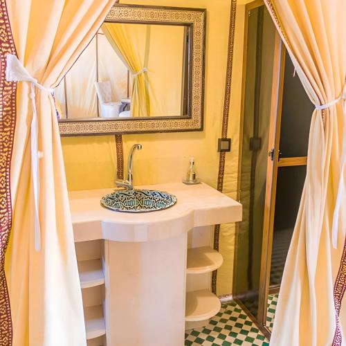 a bathroom with a sink and a mirror at Sahara Nomadic Luxury Camp in Merzouga