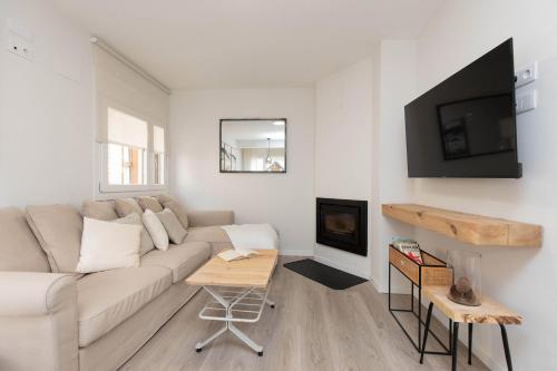 a white living room with a couch and a fireplace at Sky Biescas II by BeValle in Biescas