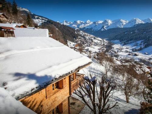 a building covered in snow with mountains in the background at Chalet Aravista - OVO Network in Le Grand-Bornand