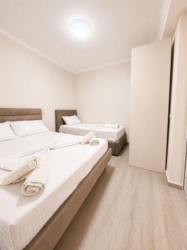 two beds in a room with white walls and wooden floors at Deon in Vlorë