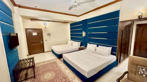 a bedroom with two beds and a blue wall at Shelton's Rezidor Peshawar in Peshawar