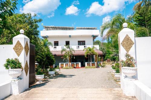 a white house with a gate and palm trees at Alles garden New Seaside in Trincomalee