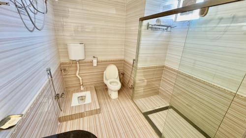a small bathroom with a toilet and a shower at Shelton's Rezidor Peshawar in Peshawar