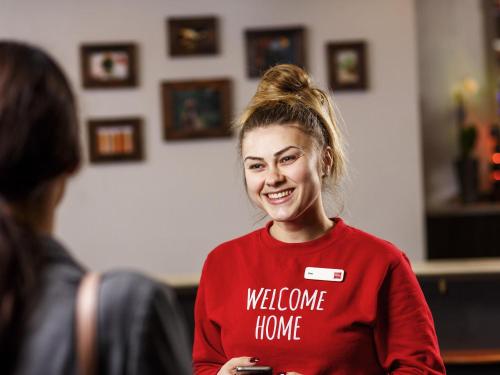 a girl in a red shirt is talking to a woman at ibis Hotel Northampton Centre in Northampton