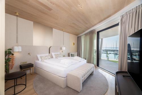 a bedroom with a large white bed and a balcony at BIRGÉS HOTEL Lifestyle and View in Balatonfüred