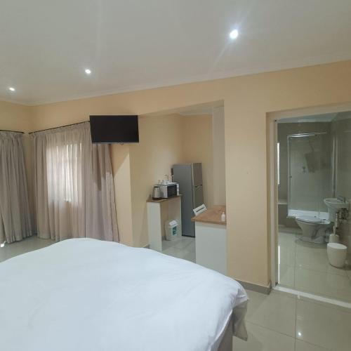 a bedroom with a white bed and a bathroom at 75 on Albert Guesthouse in Gqeberha