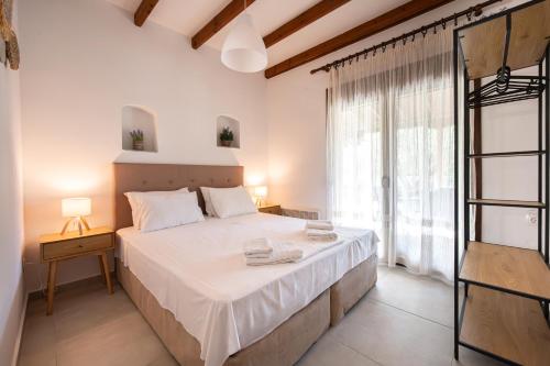 a bedroom with a large bed and a large window at Fourka Garden Villas in Fourka