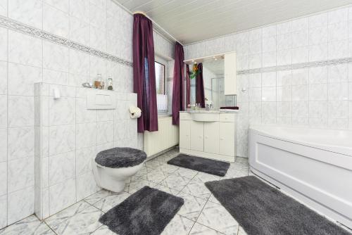a bathroom with a tub and a toilet and a sink at Ferienwohnung im Haus Katja in Dunum