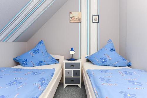 two beds in a small room with blue pillows at Ferienwohnung im Haus Katja in Dunum