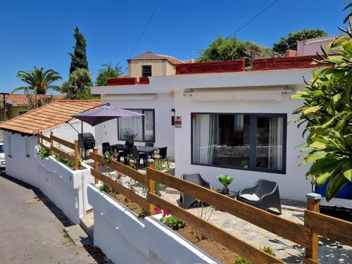a house with a fence and chairs and an umbrella at Chalet JULI Mirador in Puerto de la Cruz