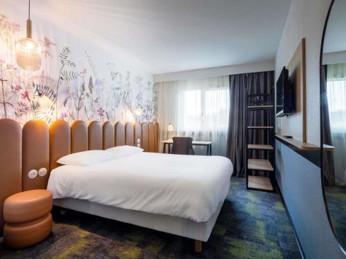 a hotel room with a bed and a wall mural at ibis Styles Pontivy centre Bretagne in Pontivy