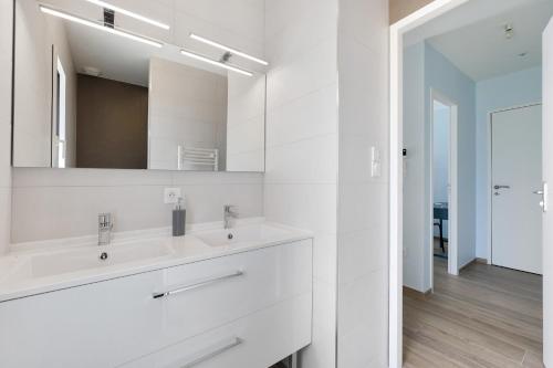 a white bathroom with two sinks and a mirror at Gite Logeraie in Le Boupère