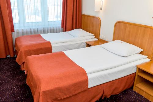 a hotel room with two beds and a desk at Hotel Beskid in Nowy Sącz