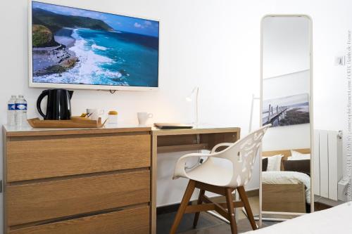 a bedroom with a desk with a television on a wall at Le Domaine de Wail Legends Resort in Wail