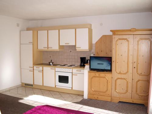 Il comprend une cuisine avec des placards blancs et une télévision. dans l'établissement Ferienwohnungen Luxner, à Fügen