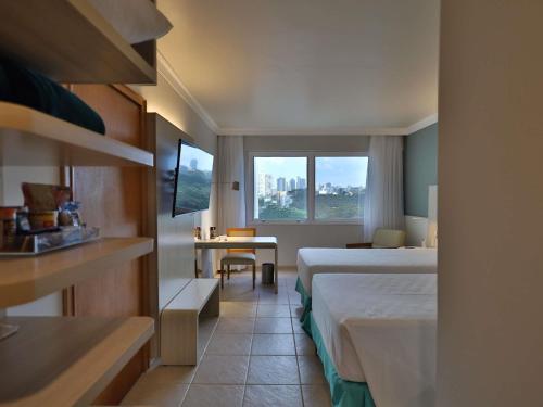 a hotel room with two beds and a window at Mercure Salvador Rio Vermelho in Salvador