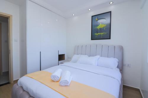 a bedroom with a white bed with two towels on a tray at one bedroom airbnb with swimmingpool, kiambu road in Kiambu