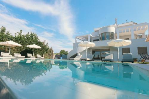 a swimming pool with chairs and umbrellas next to a house at Casa Grande Private Luxury Villa in Alykes Potamou