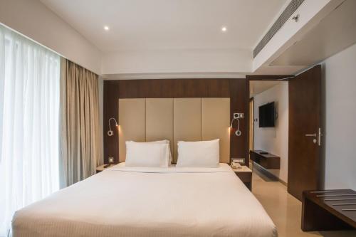a bedroom with a large bed and a large window at Ramee Techome in Mumbai