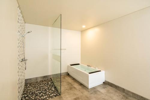 a bathroom with a tub and a glass shower at Shankara Munduk Bali in Munduk