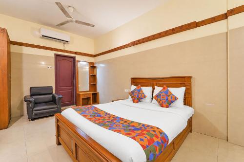 a bedroom with a bed and a chair in it at FabHotel Sca - Gandhipuram in Coimbatore